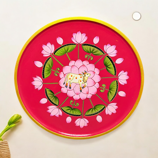 A decorative wall plate featuring artistic representations of cows and a tree with a stylized design in black, green, white, and yellow colors.