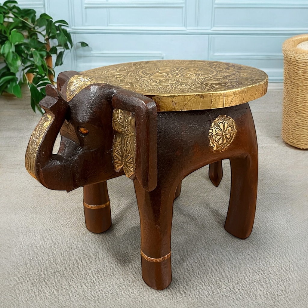 A handcrafted wooden elephant-shaped stool with brass inlay detailing on the top and sides, placed on a light background.